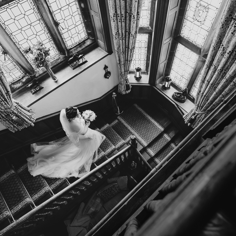 Bride walks down stairs at Wigfair Hall during a North Wales wedding