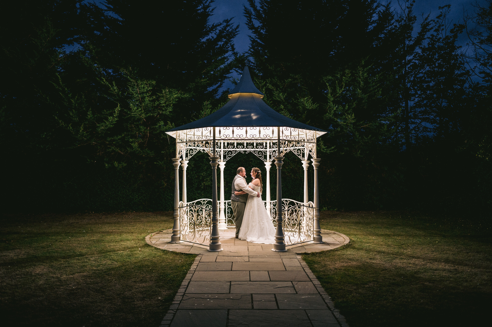 Bride & Groom embrace in pagoda outside Faenol Fawr wedding venue at night