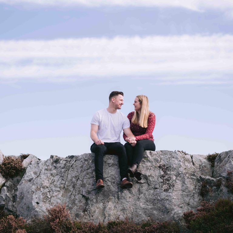 Engaged couple sitting on top of Hope Mountain North Wales
