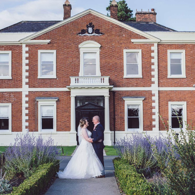 Bride & Groom stand in front of the DoubleTree Hilton Chester for wedding photos
