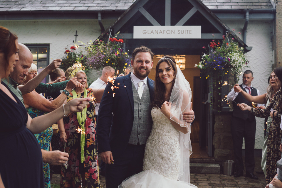 Bride & Groom walk through guests holding sparklers after wedding at Wild Pheasant hotel