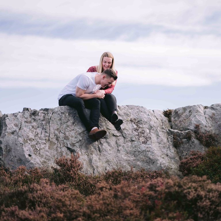 Engaged couple laughing on top of Hope Mountain North Wales