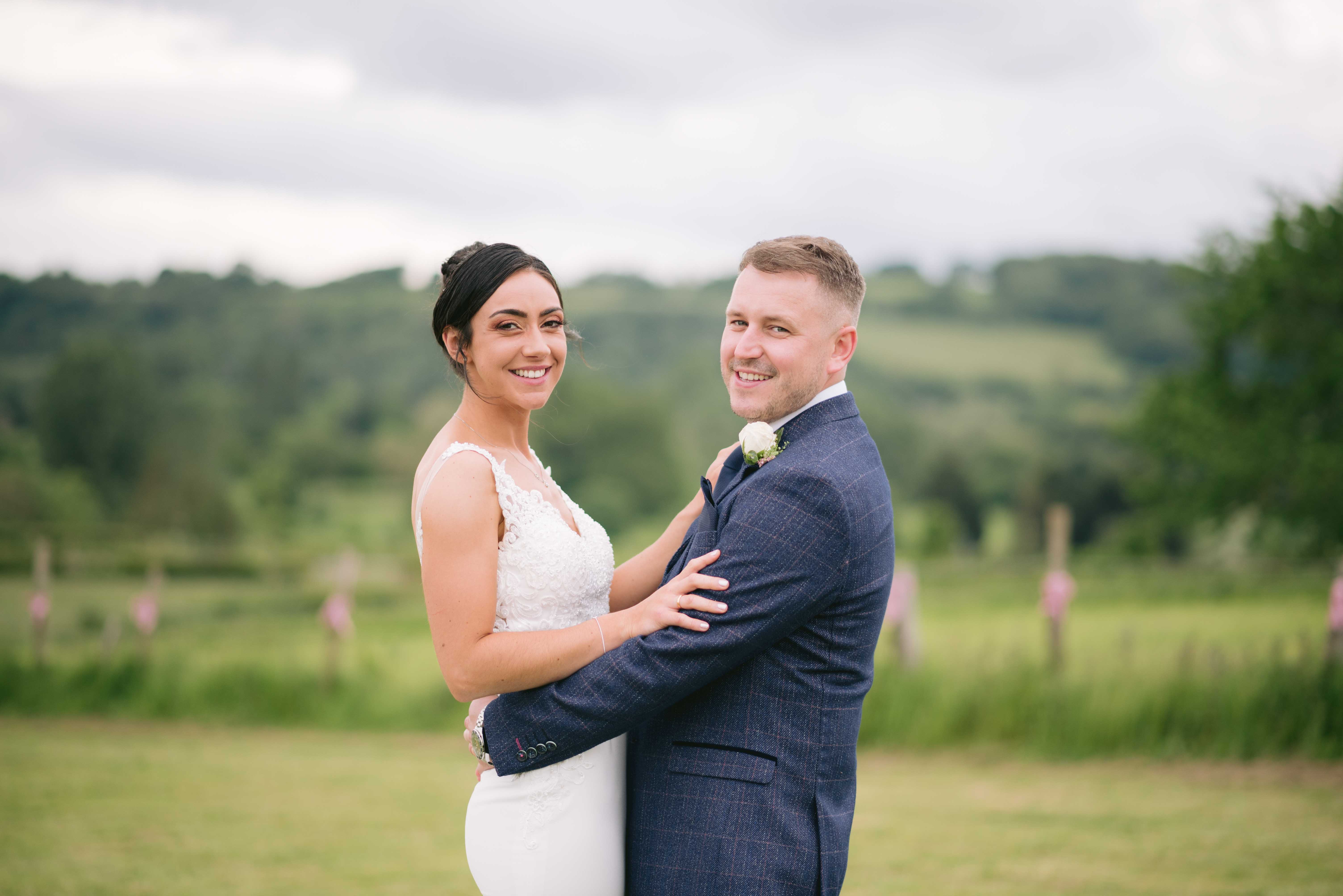 Bride & Groom smile on field during marquee wedding in Ruthin North Wales