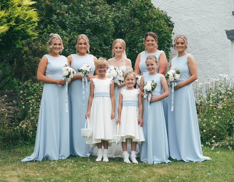 Bride & Bridesmaids stand outside cottage during wedding portraits in Ruthin, North Wales
