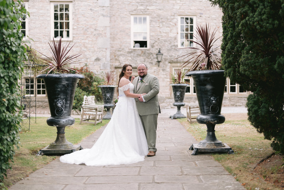 Bride & Groom embrace in front of Faenol Fawr Hotel during wedding portrait photographs 