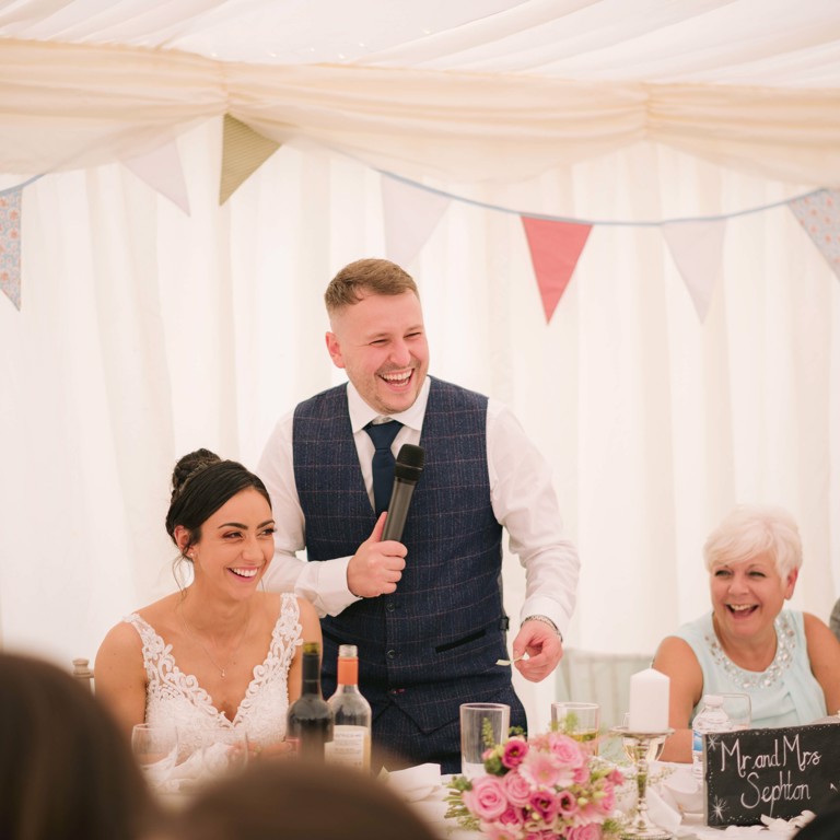Bride and Groom laugh at speech during wedding in Penyffordd North Wales