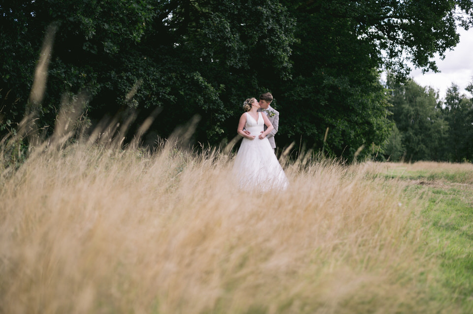 Bride & Groom kiss in the long crass during wedding photography at the Oak Tree Peover