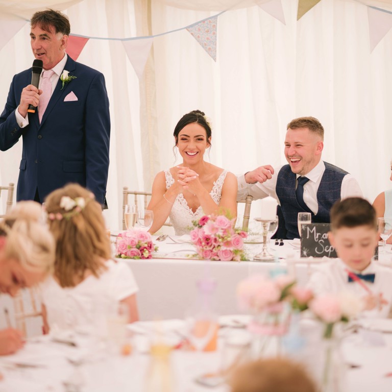 Bride & Groom laugh during Fathers speech in marquee at North Wales wedding
