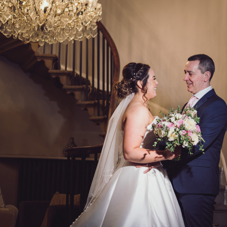 Bride & Groom look at each other near staircase at Rossett Hall Hotel