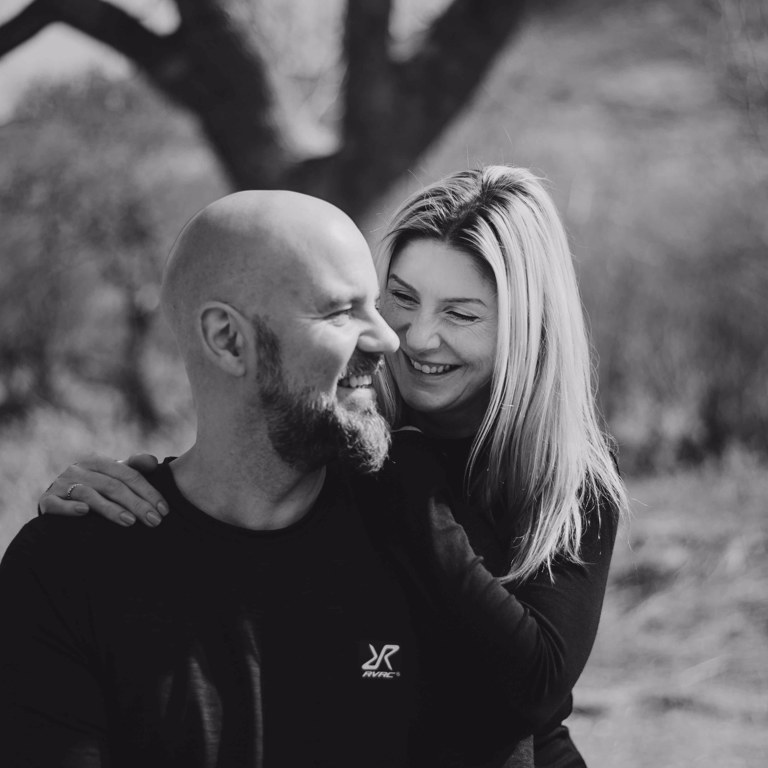 Couple pose on bench during pre wedding photo shoot in North Wales