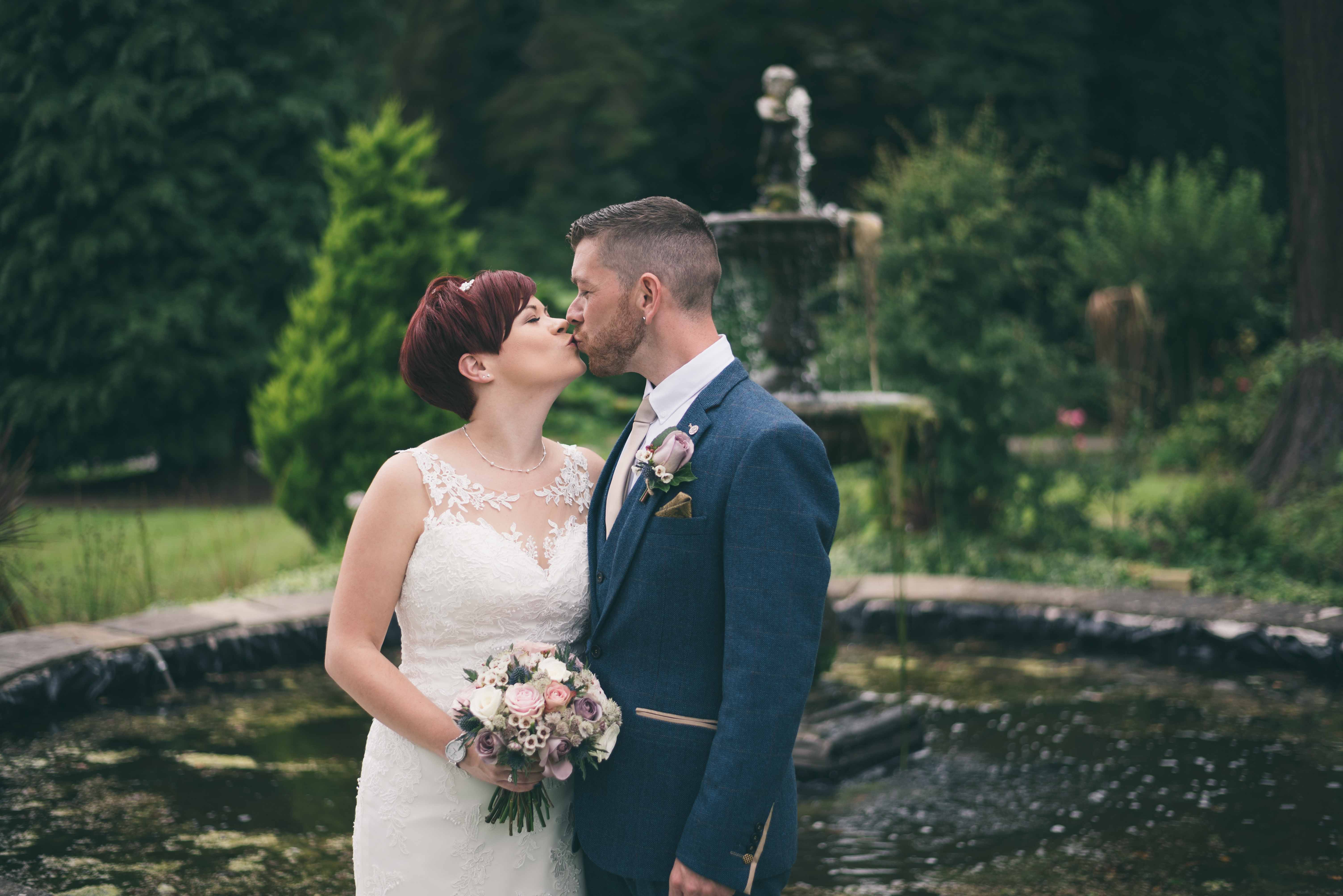 Bride & Groom kiss by fountain at Highfield Hall, Northop
