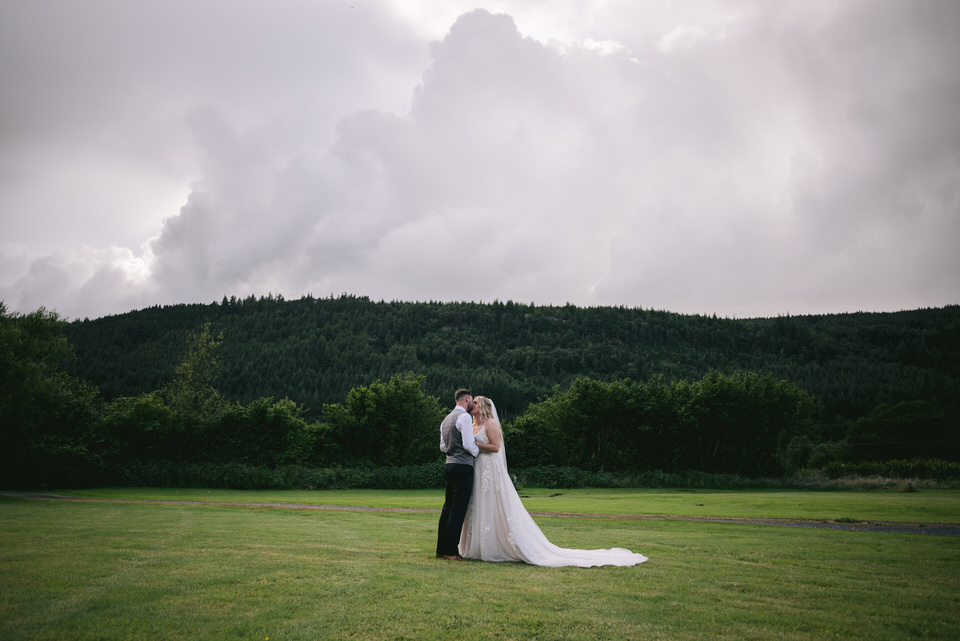 Bride & Groom kiss on field during Hafod Farm wedding photography