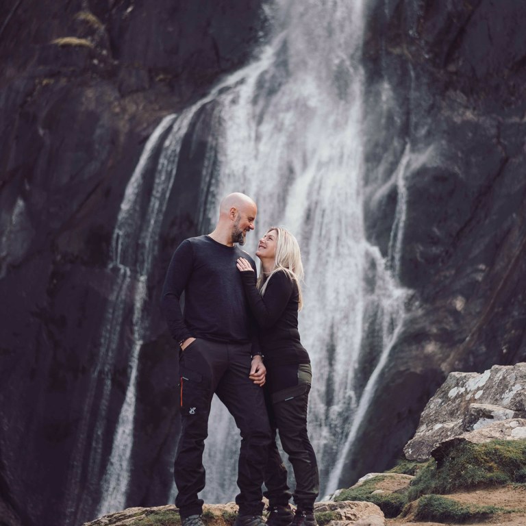 Couple look at each other in front of Aber Falls North Wales