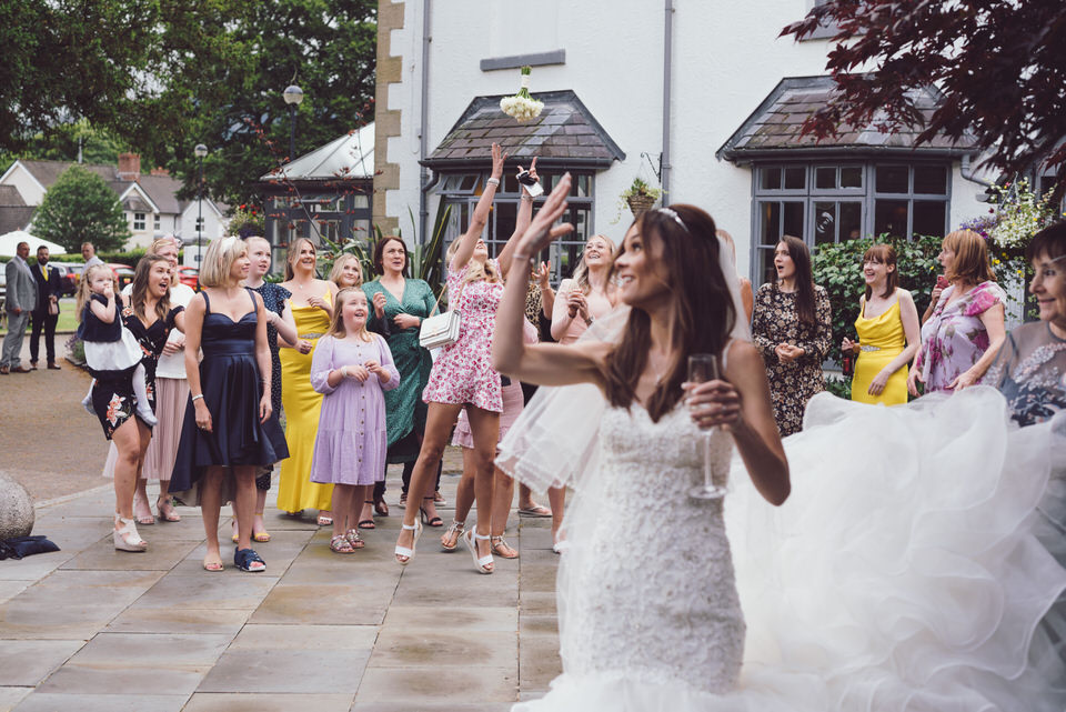 Bride throws flowers during bouquet toss at the Wild Pheasant Hotel as guests try to catch it
