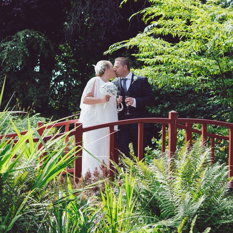 Bride & Groom kiss on red bridge at Chester Zoo wedding
