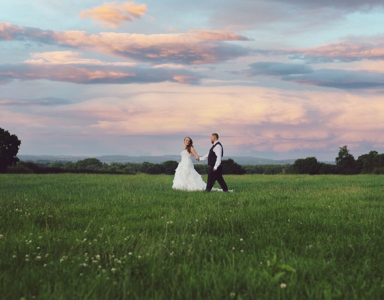 Bride & Groom walk through field during photos at sunset in North Wales 