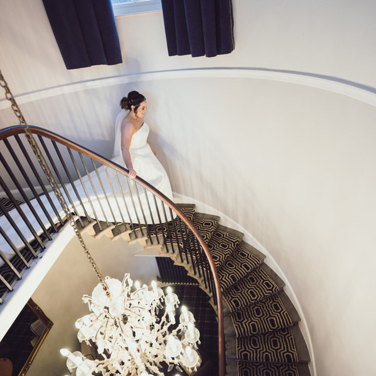 Brides walks down spiral staircase at Rossett Hall wedding