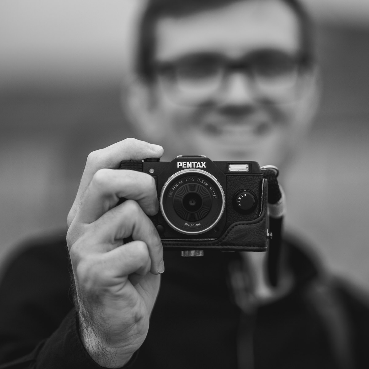 North Wales Wedding Photographer Andrew Baines, holds out camera