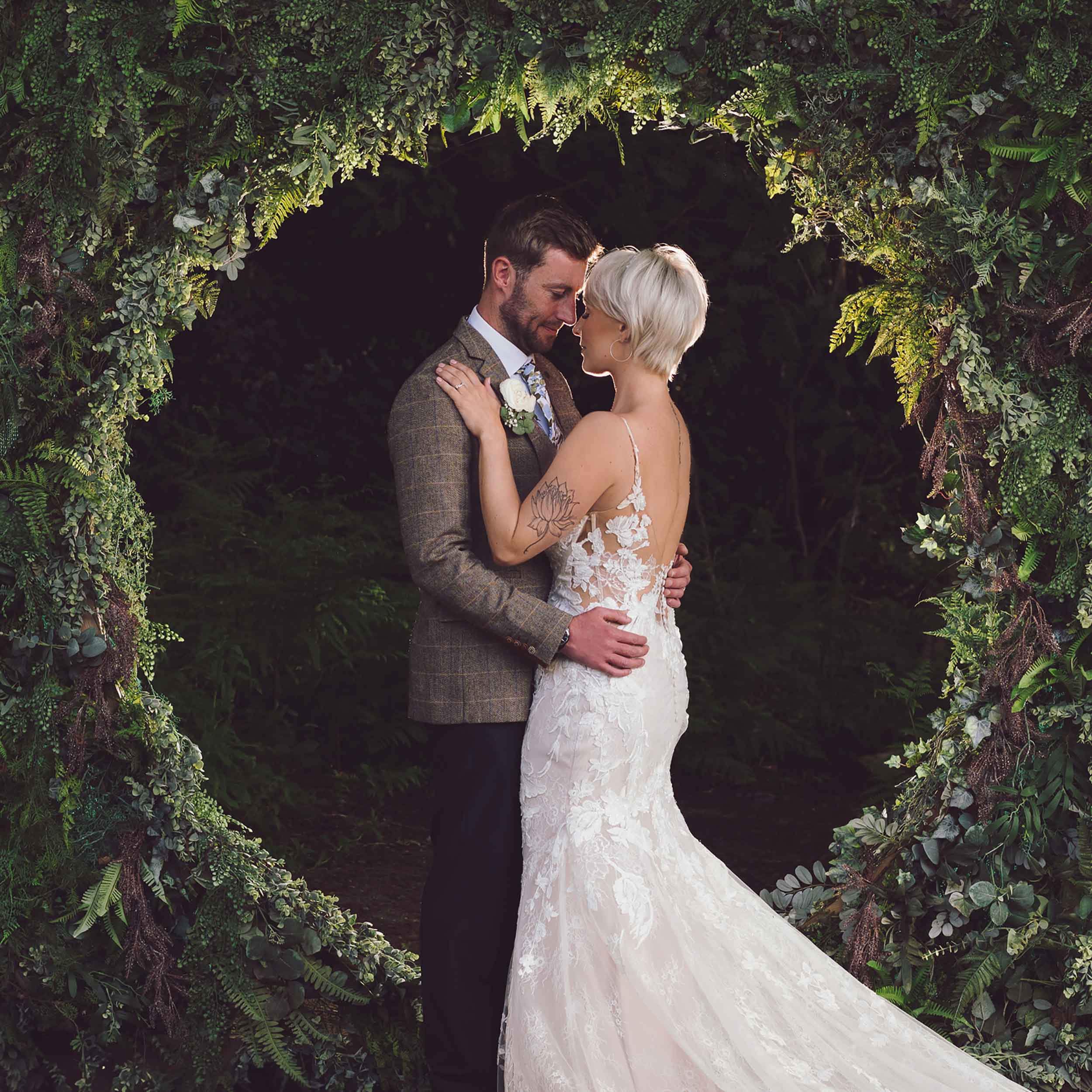 Bride & Groom embrace in front of foliage circle at Cheshire woodland weddings