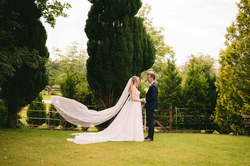 Bride & Groom laugh during wedding day portrait session in gardens at Highfield Hall
