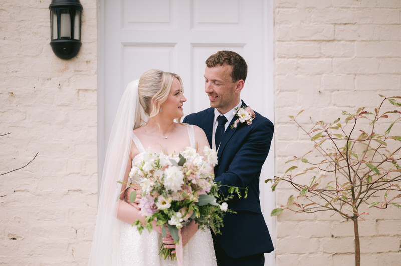 Bride & Groom stand in front of vintage car with Highfield hall in background