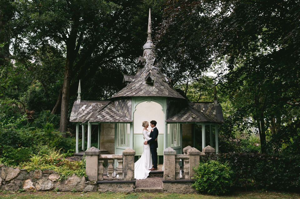 Couple stand in outdoor pergoda in the grounds of Chateau Rhianfa in Anglesey North Wales