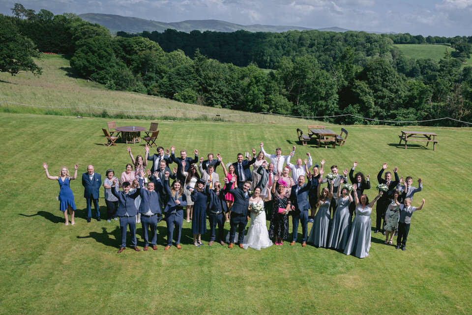 Ariel group shot of wedding guests in the gardens at wedding in Wigfair Hall