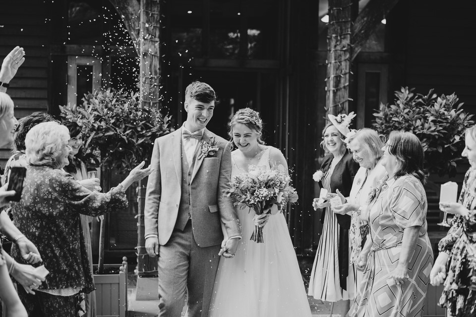 Bride & Groom walk between guests whilst they throw confetti at the Oak Tree Peover