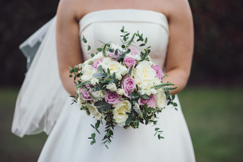 Close up photograph of Bride holding bouquet of cream & pink flowers at Rossett Hall Hotel