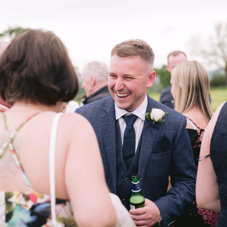 Groom laughs with guests at Marquee wedding in Penyffordd North Wales