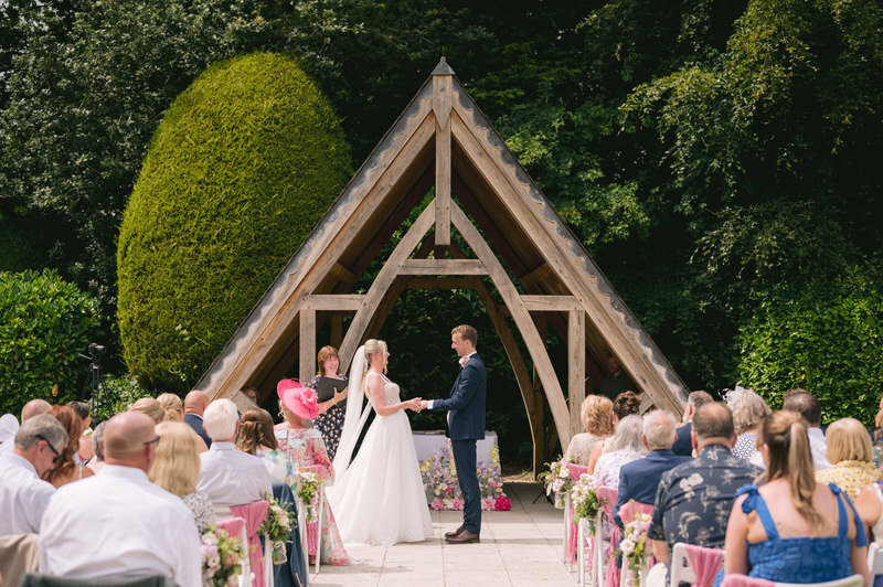 Bride & Groom cut wedding cake in front of a neon sign at Highfield Hall