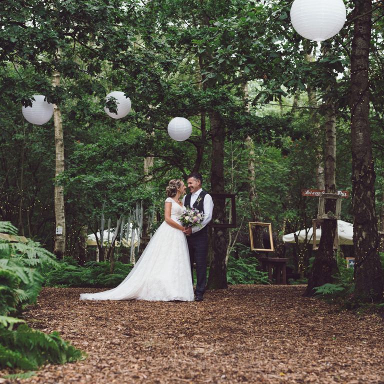 Bride & Groom look at each other beneath trees at Cheshire Woodland Weddings