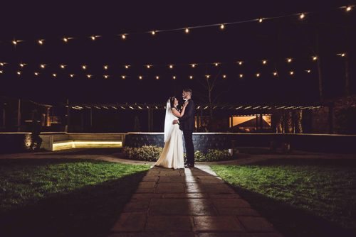 Bride & Groom hold each other at night time outside Lion Quays North Wales