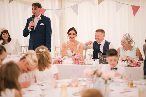 Bride & Groom laugh during wedding speeches in a marquee in Ruthin