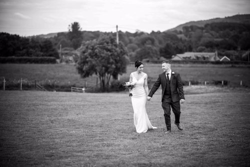 Bride & Groom walk across field in North Wales during Marquee wedding
