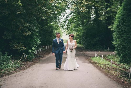 Bride & Groom walk up driveway and laugh during wedding at Highfield Hall Northop