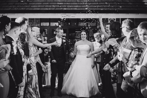 Guests throw confetti on couple outside of Rossett Hall Hotel wedding