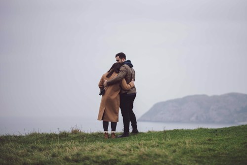 Couple hug and look out towards the sea in Llandudno North wales pre wedding photo session