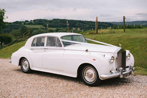 Vintage white car arrives at field in Ruthin for Marquee wedding