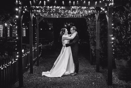 Bride & Groom stand under Fairy-lit pagoda outside of Rossett Hall wedding