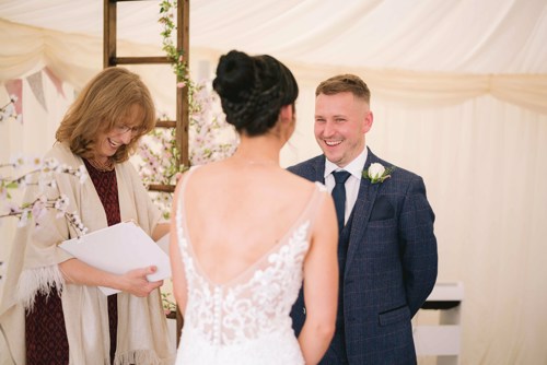 Groom laughs during wedding ceremony in a Marquee in Ruthin