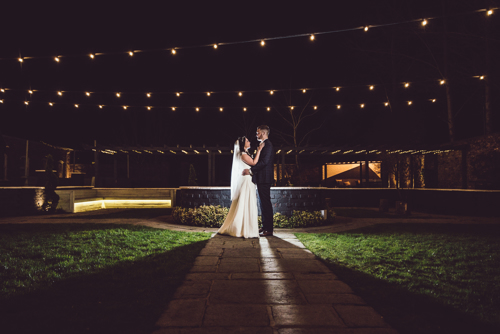 Bride & Groom night time portrait under fairy lights outside local wedding venue