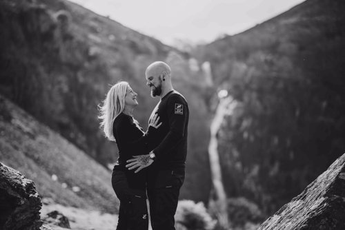 Couple look lovingly at each other in front of North Wales waterfall during pre wedding photo shoot