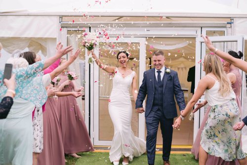 Bride & Groom walk through a shower of confetti from their wedding guests