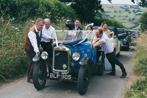 Wedding guests push car up hill on the way to Ruthin wedding in North Wales