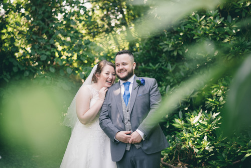 Bride leans on Grooms shoulder and laughs at her North Wales wedding photographer