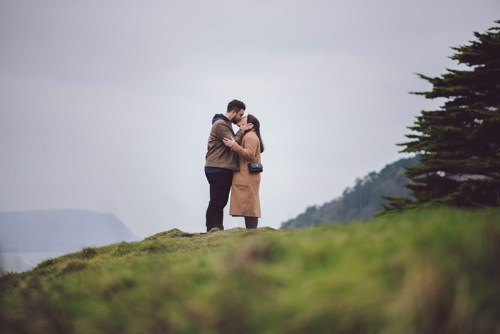 Couple kiss on hill during pre wedding shoot in Llandudno North Wales